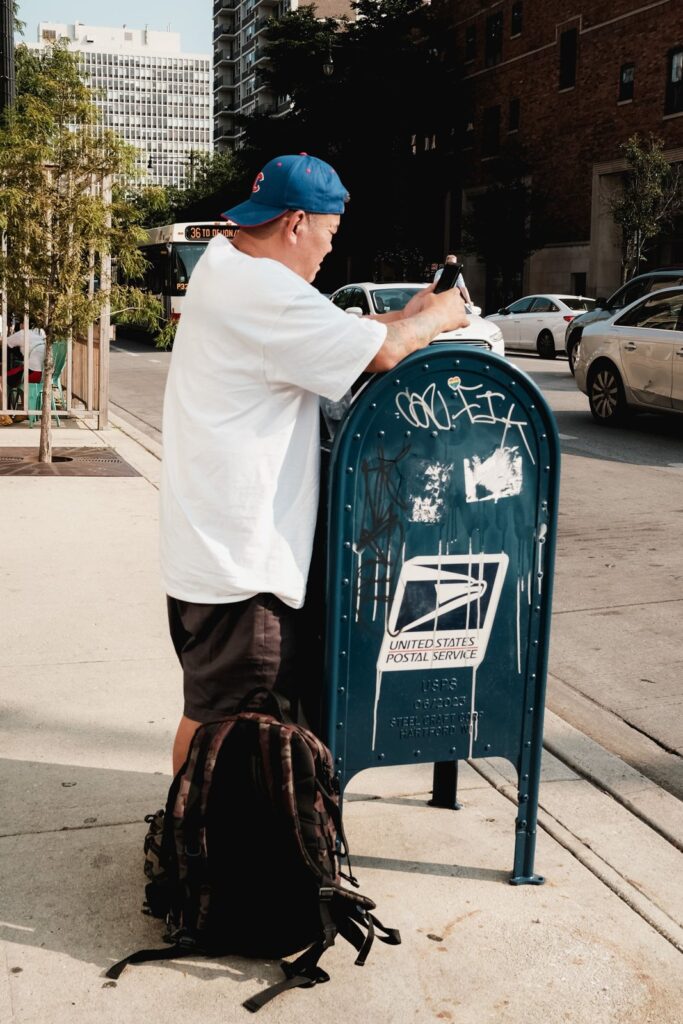 A man at a U.S. Postal Service mailbox on a Chicago street, the kind of spot where you'd mail a credit report dispute letter