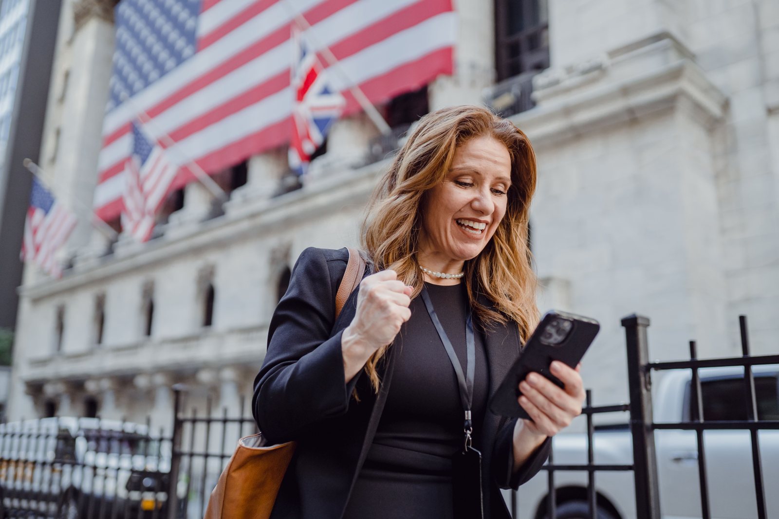 A smiling woman checking her phone on a New York City street lined with American flags