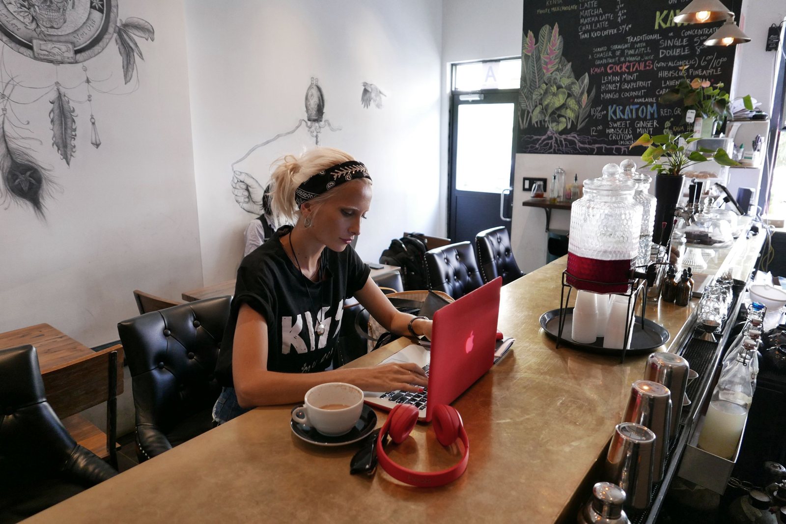 A woman at a Brooklyn cafe laptop doing a quick weekly money reset with coffee beside her