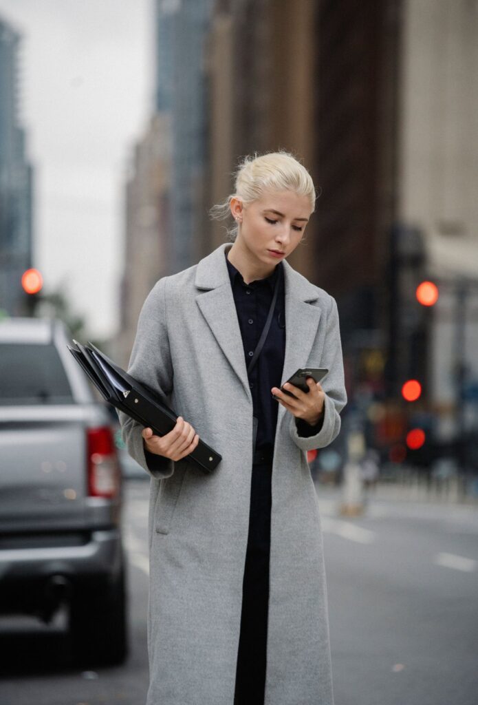 A woman on a New York street looking at her phone, a common trigger when you want to stop comparing yourself to others financially
